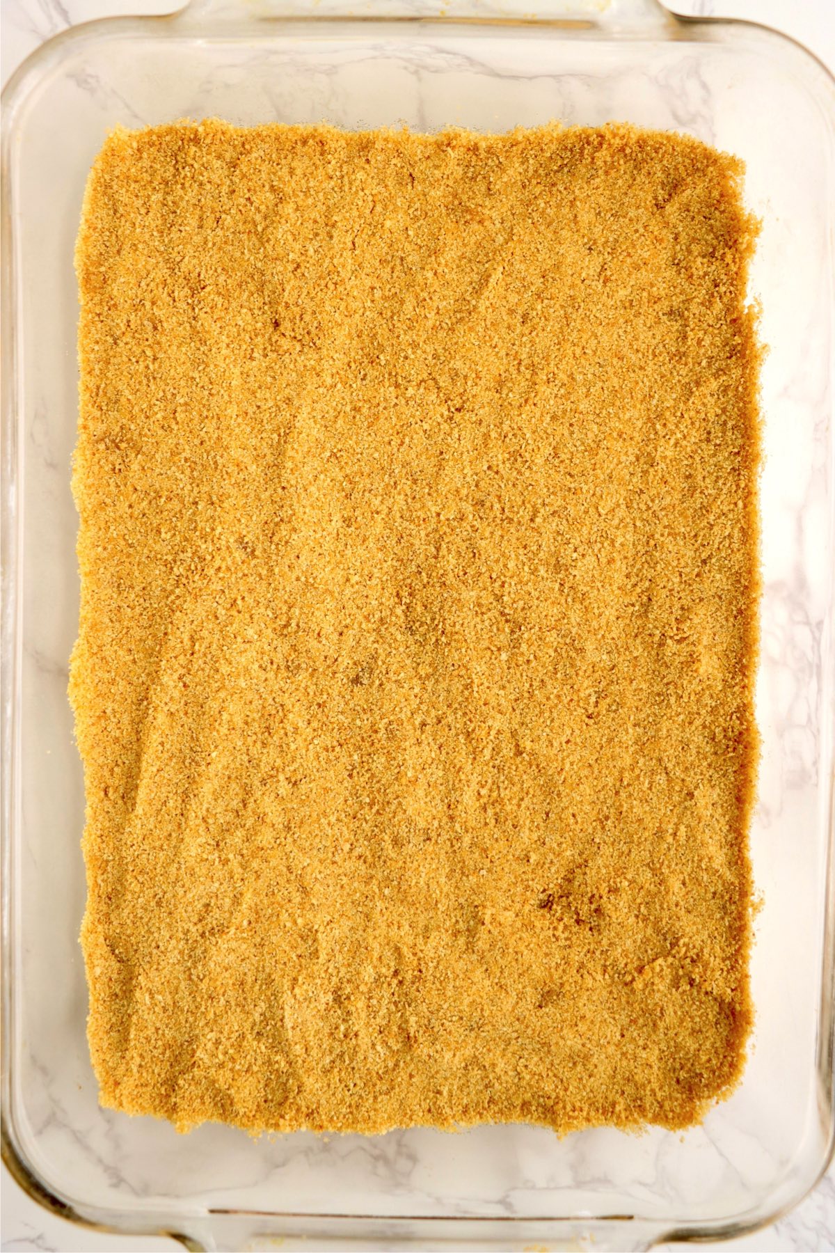 Graham crackers pressed into the bottom of a glass cake pan.