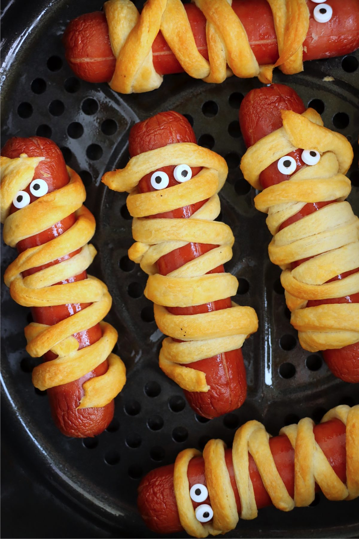 Hotdogs with googly eyes wrapped in strips of crescent rolls.