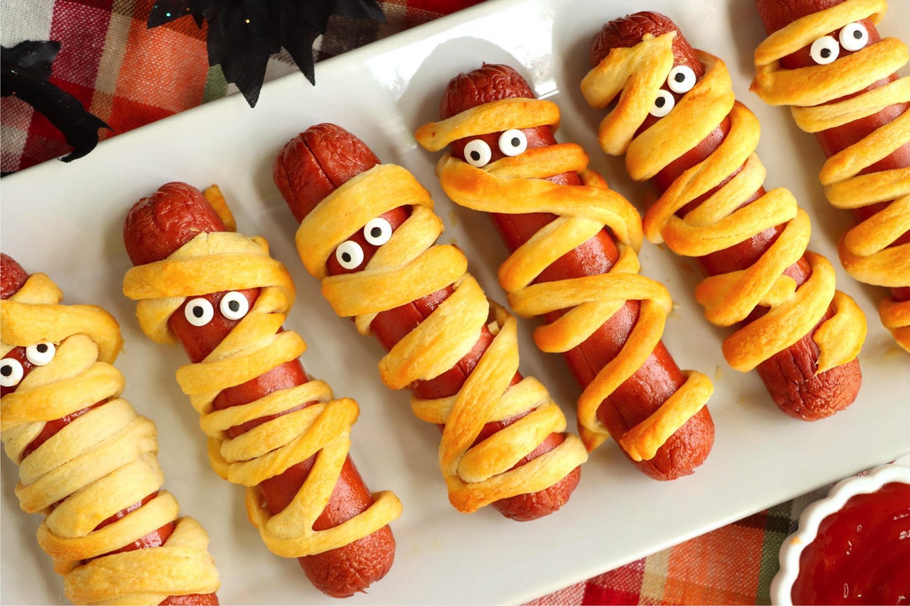 White platter filled with Halloween mummy hotdogs.