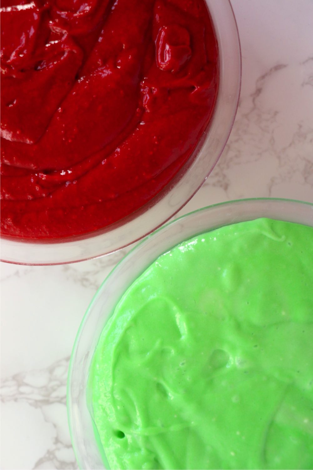 Glass mixing bowls filled with red and green cake mix.