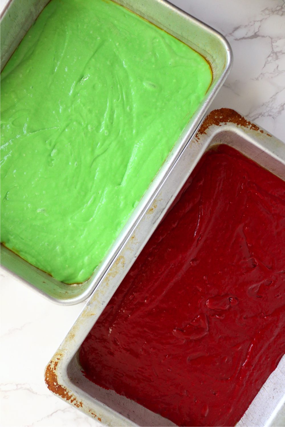 Cake pans filled with green and red cake mix.