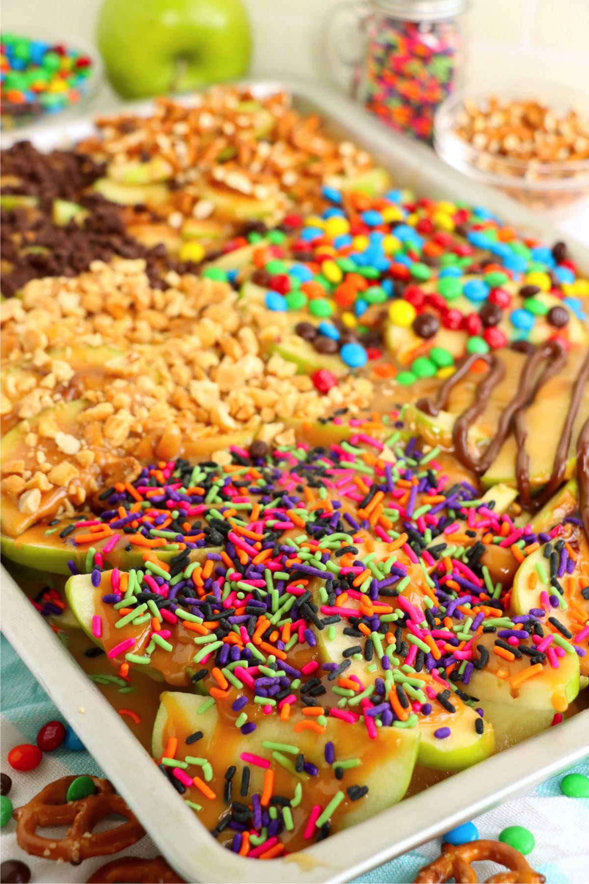 A large sheet pan covered with sliced apples, caramel and toppings.