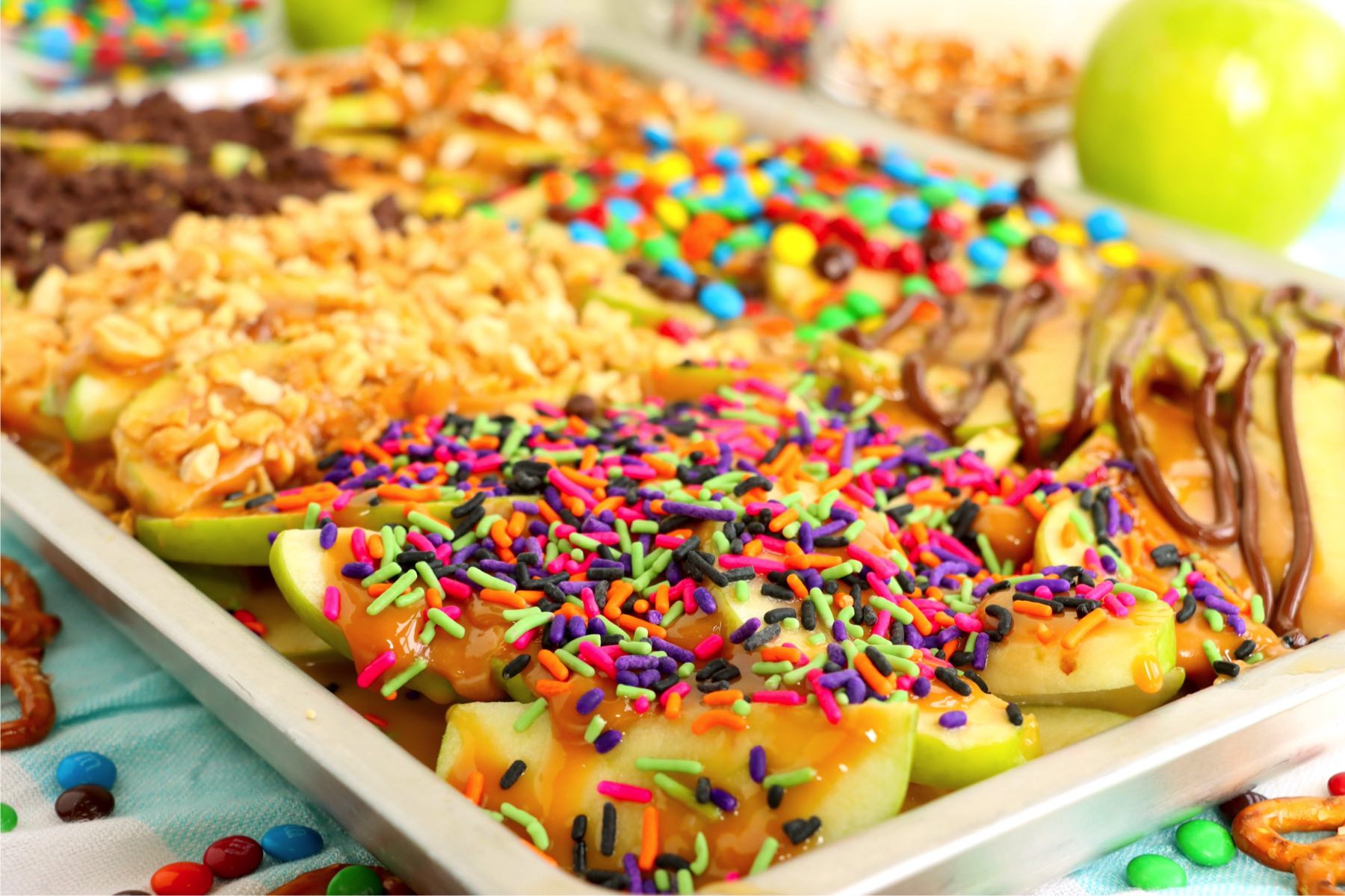 Sheet pan filled with Granny Apple slices and covered in caramel and toppings.