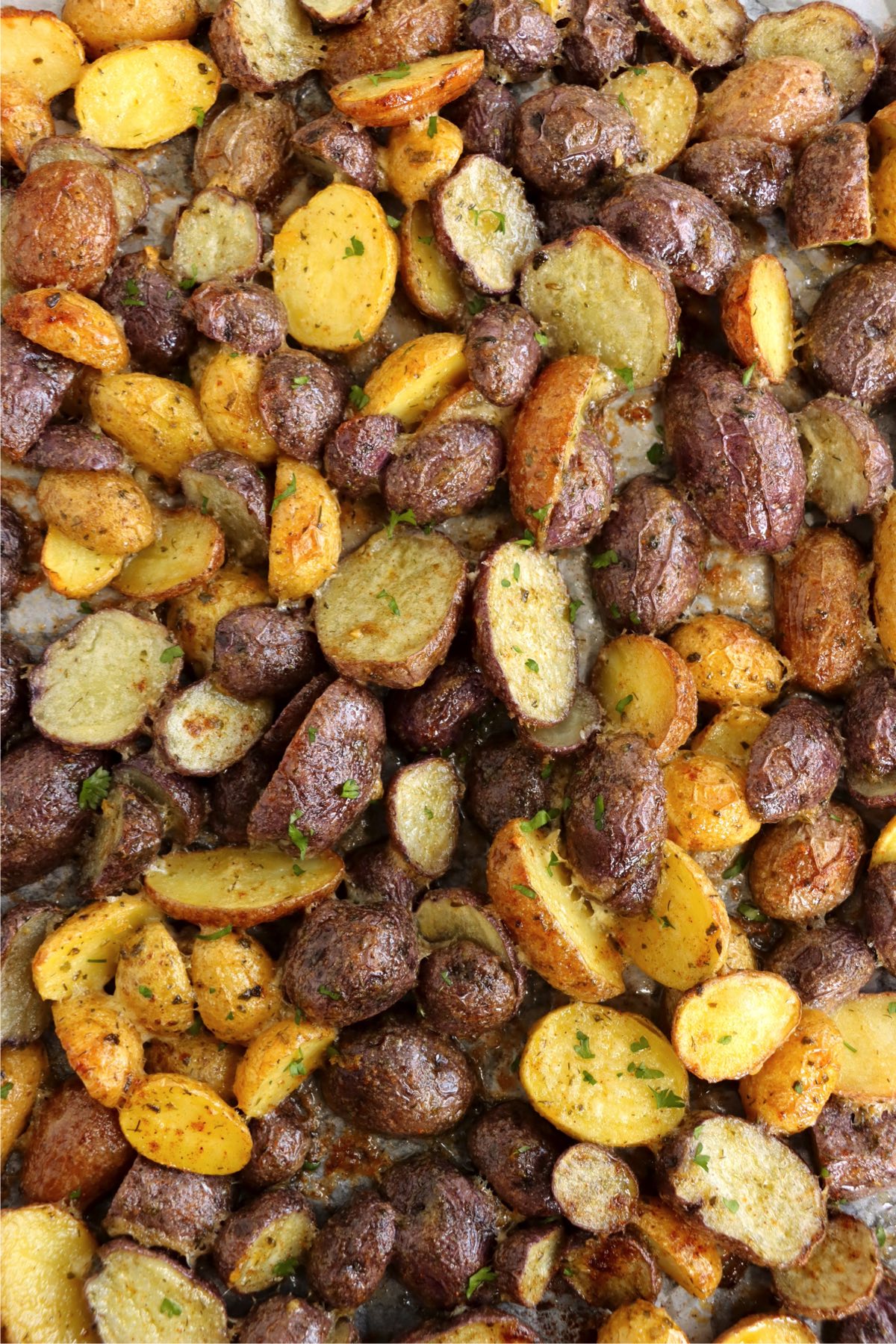 A sheet pan filled with halved, roasted bi-color potatoes.