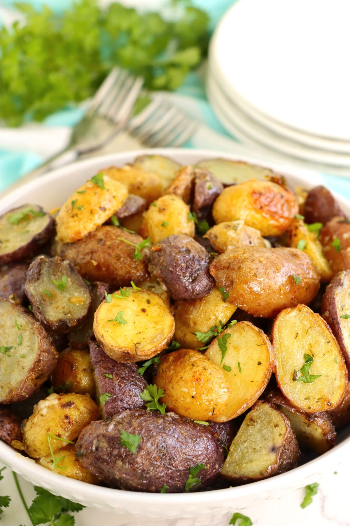 Bowl of roasted potatoes garnished with parsley.