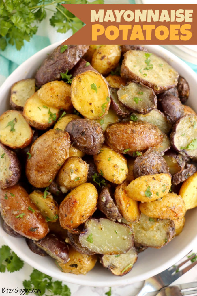 Large white bowl of roasted potatoes surrounded by parsley.