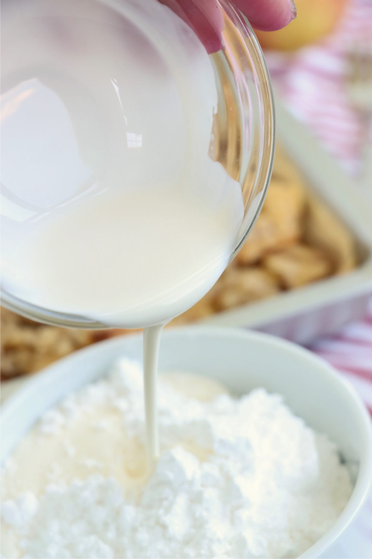 Pouring cream into a bowl of powdered sugar.