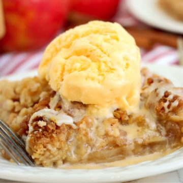 Piece of apple pie with ice cream on a white plate.