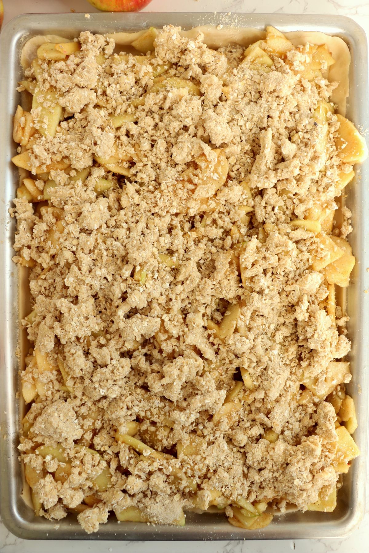 Jelly roll pan of apple pie covered with crumble topping.