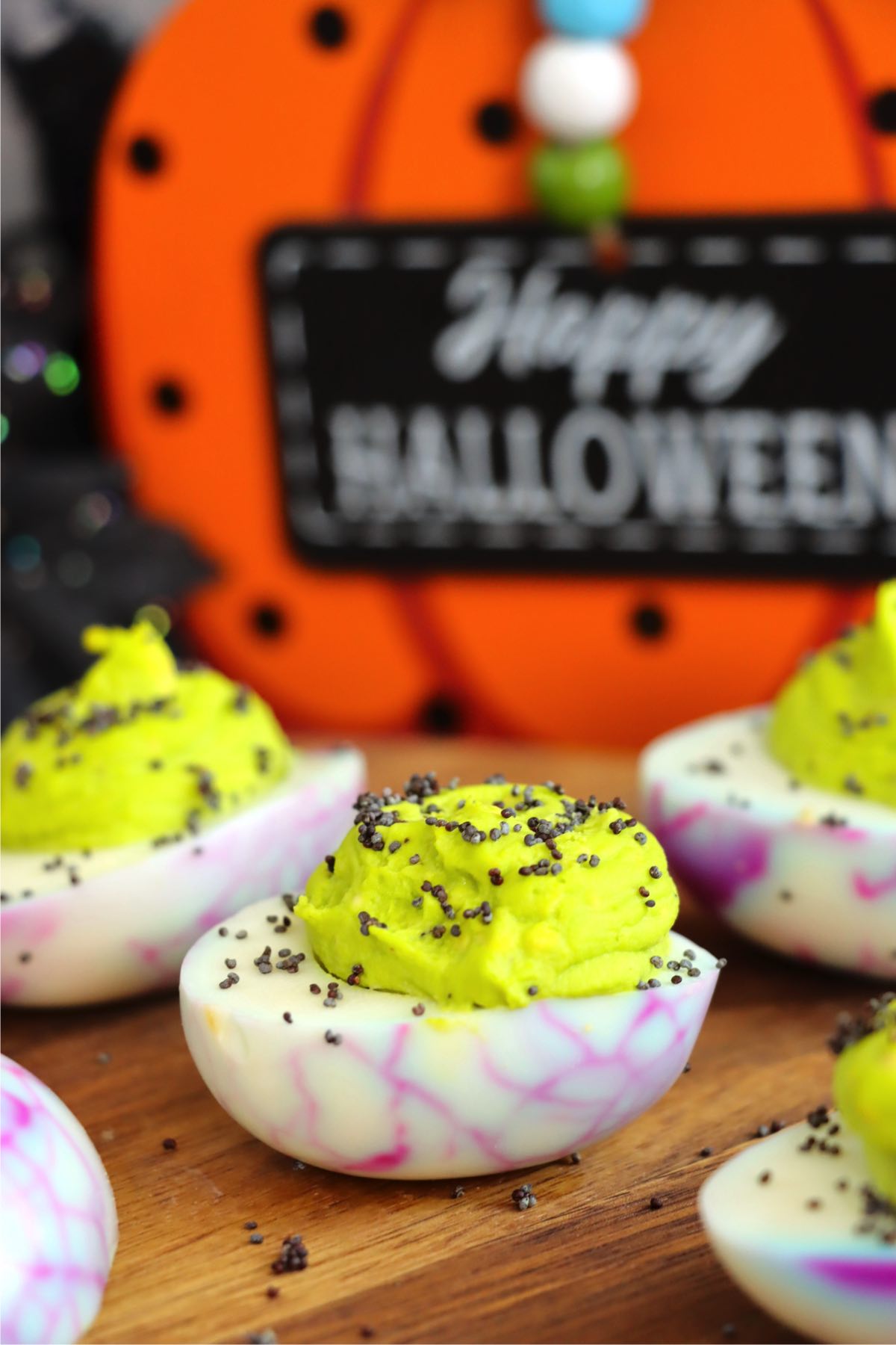 Deviled eggs decorated for Halloween sitting on a wooden table.