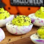 Wooden tabletop displaying Halloween-themed deviled eggs.