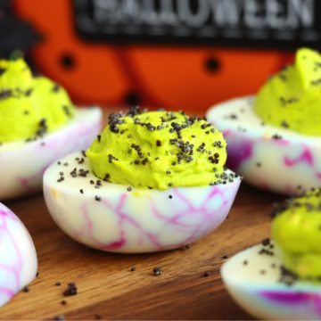 Wooden tabletop displaying Halloween-themed deviled eggs.