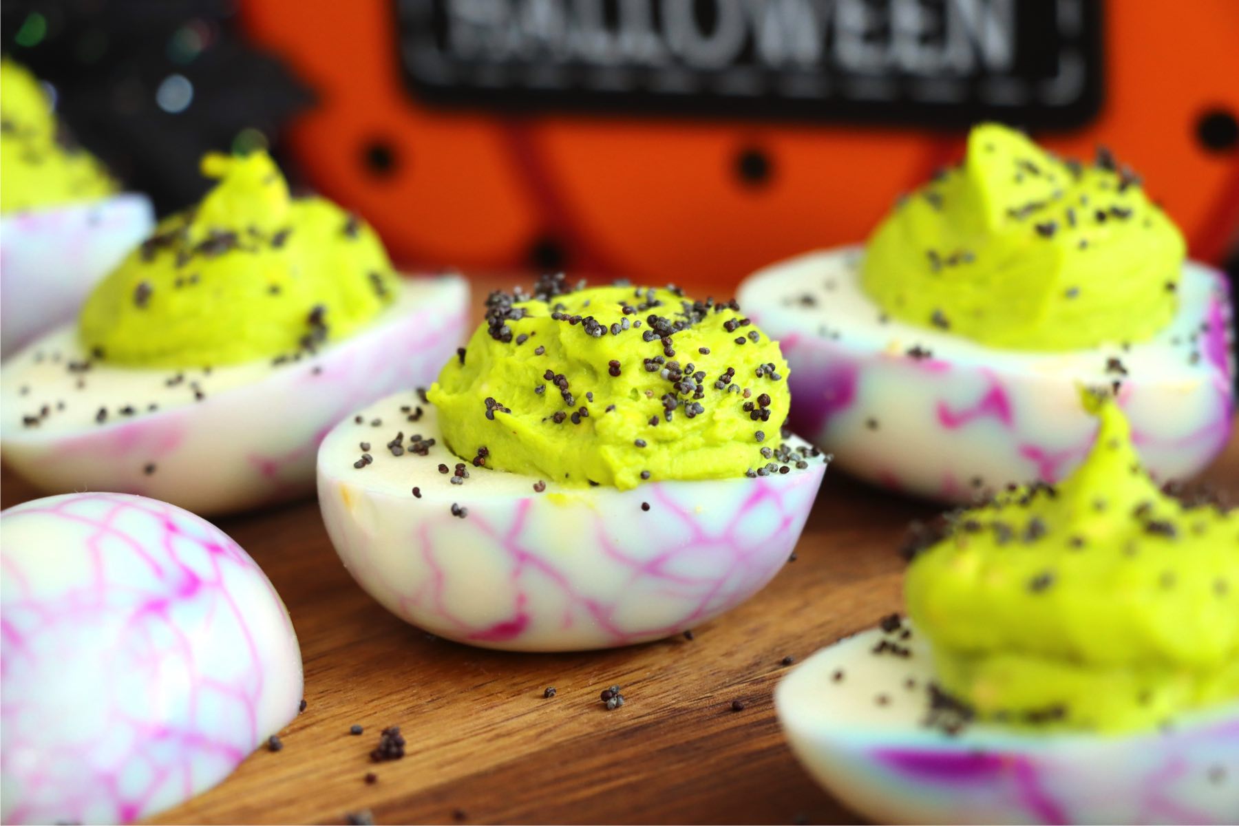 Wooden tabletop displaying Halloween-themed deviled eggs.