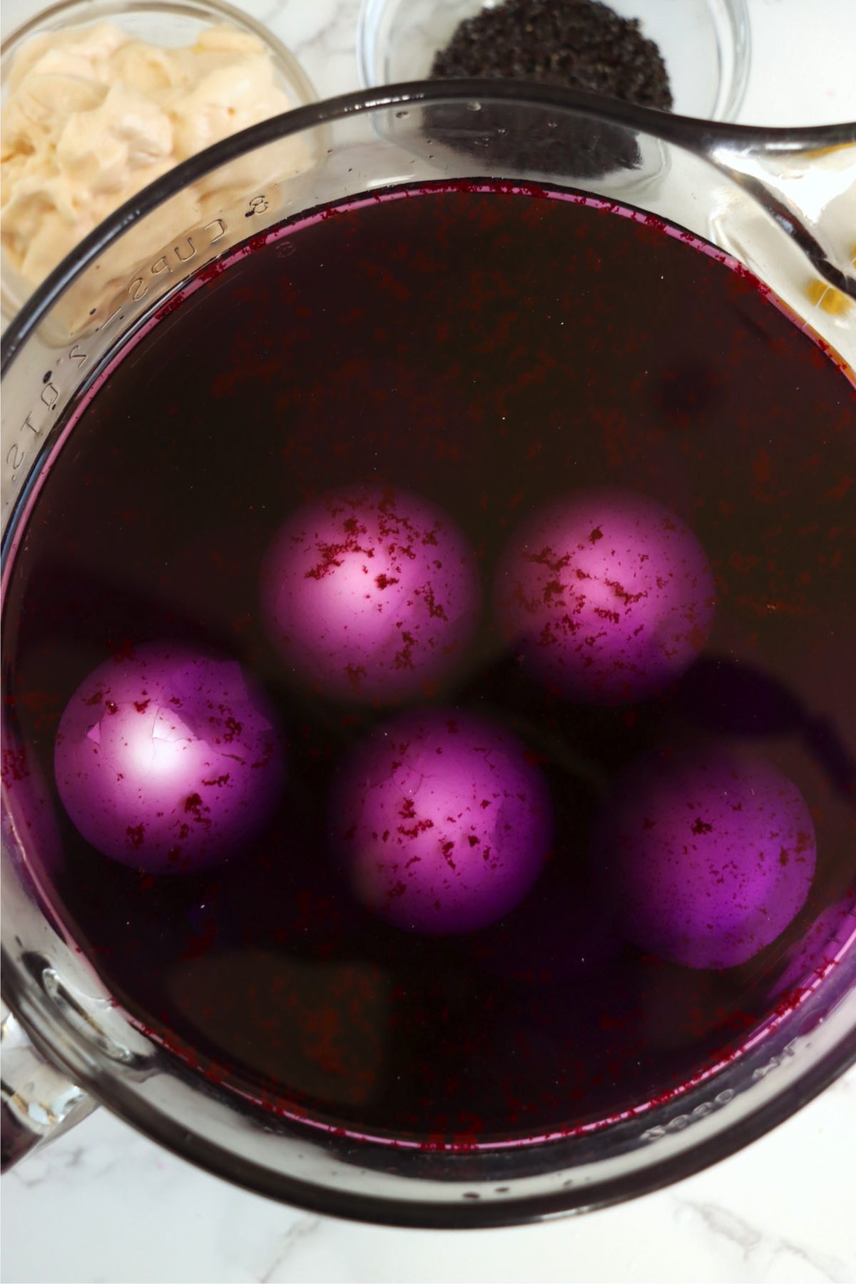 Cracked hard boiled eggs immersed in purple dye.