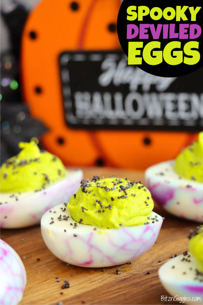 Halloween-inspired deviled eggs displayed on a wooden tabletop.