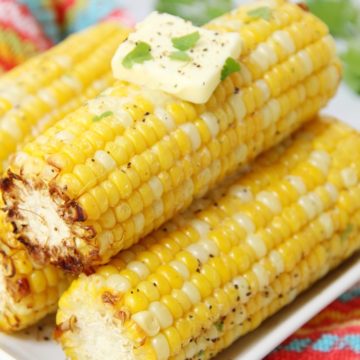 Air fryer corn on the cob on serving dish with butter.