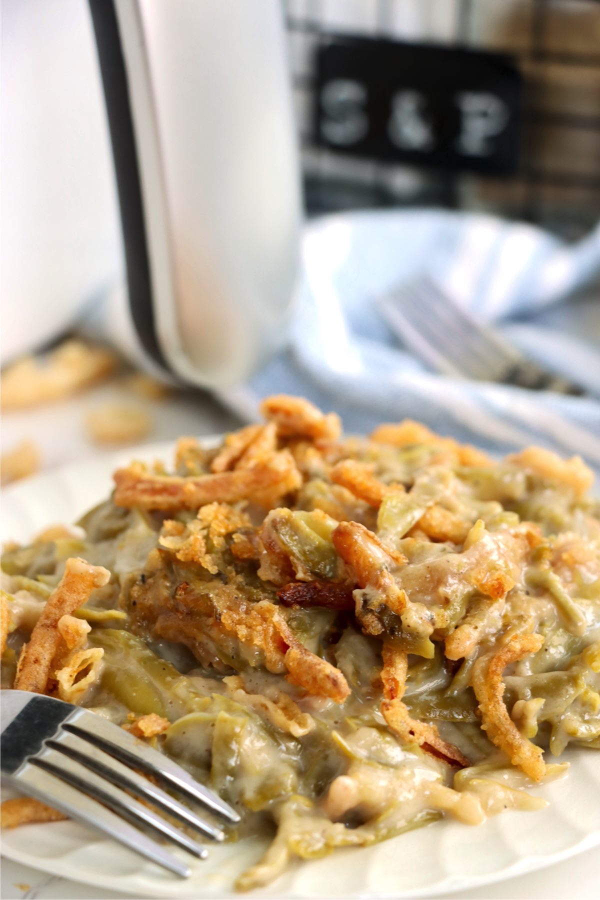 White plate filled with green bean casserole in front of air fryer.