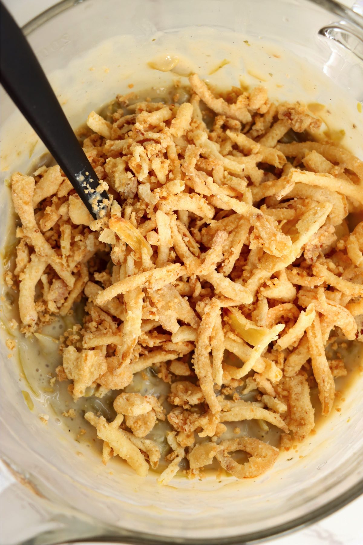 Bowl of green beans covered with fried onions.