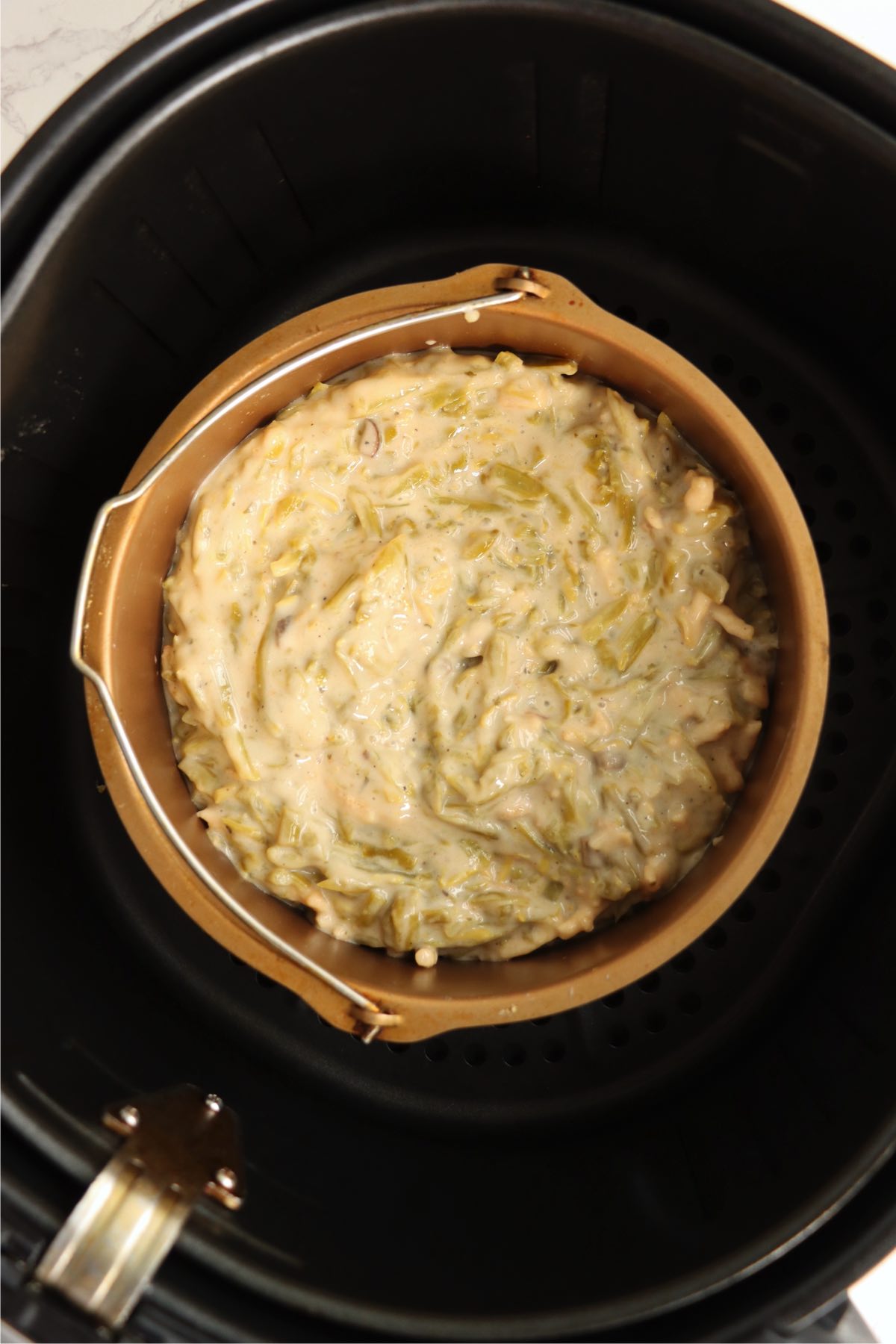 Green bean casserole in a bowl sitting in an air fryer.