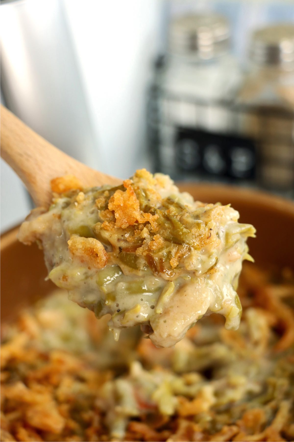 Spoon scooping up green bean casserole from a bowl.