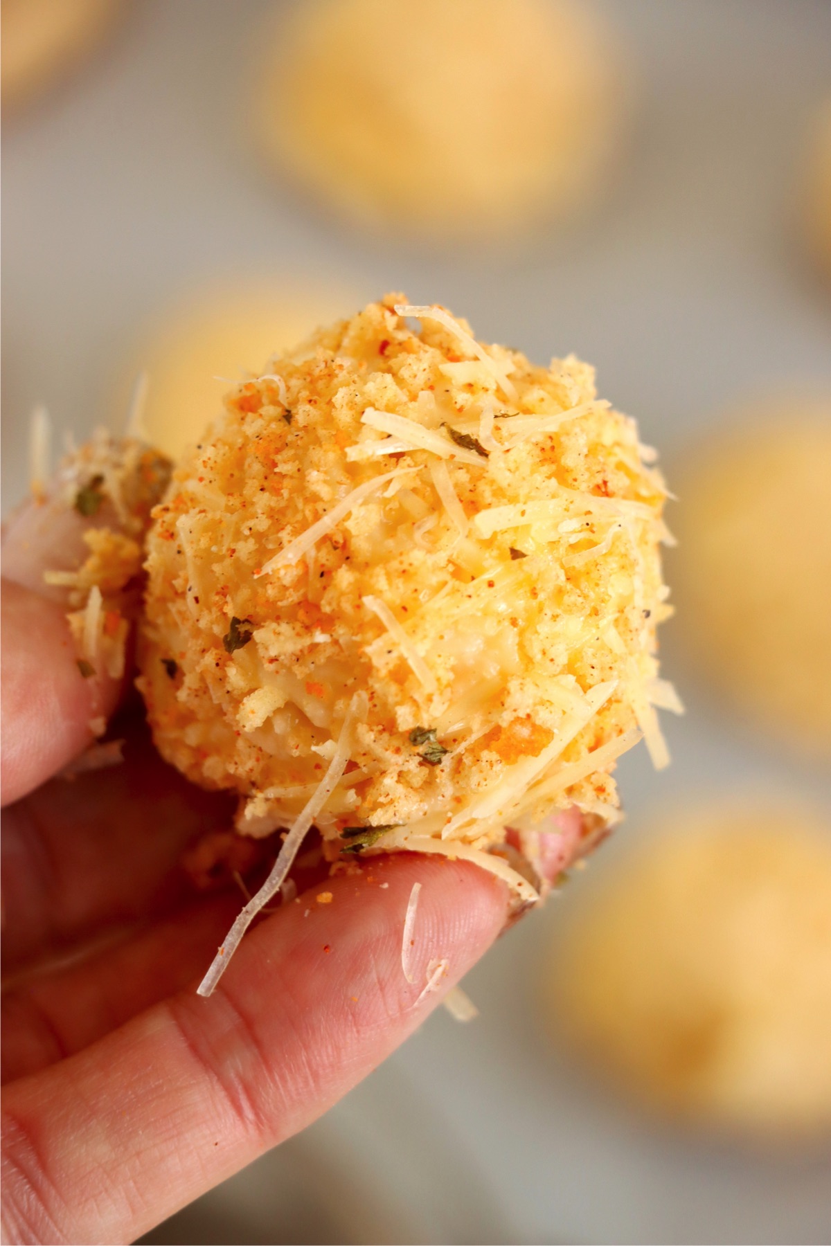 Mac and cheese bite dipped in bread crumbs and shredded cheese.