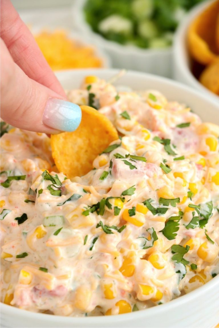 Frito dipping into Mexicorn dip in glass bowl.