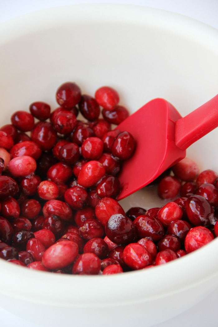 Mixing cranberries with egg whites in glass mixing bowl.