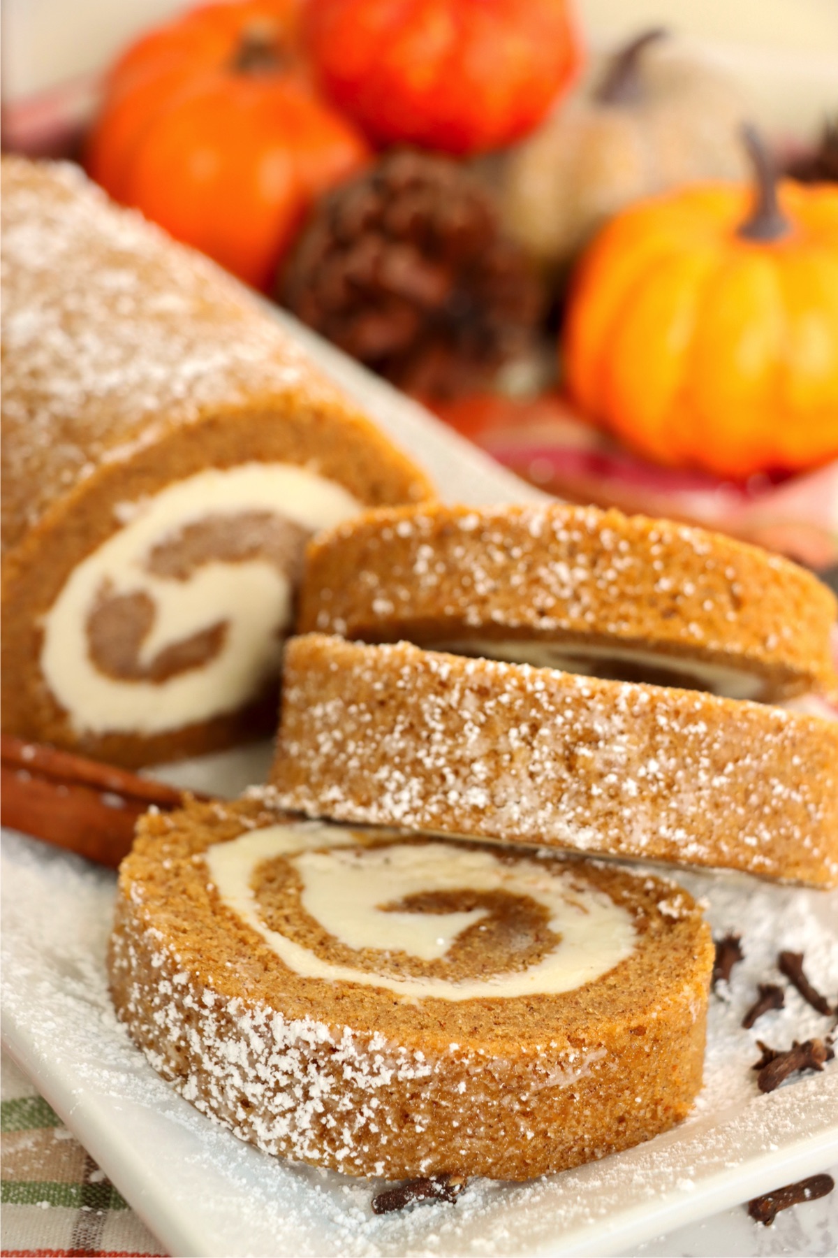 Easy pumpkin roll recipe with three sliced pieces showing a perfect spiral filling.