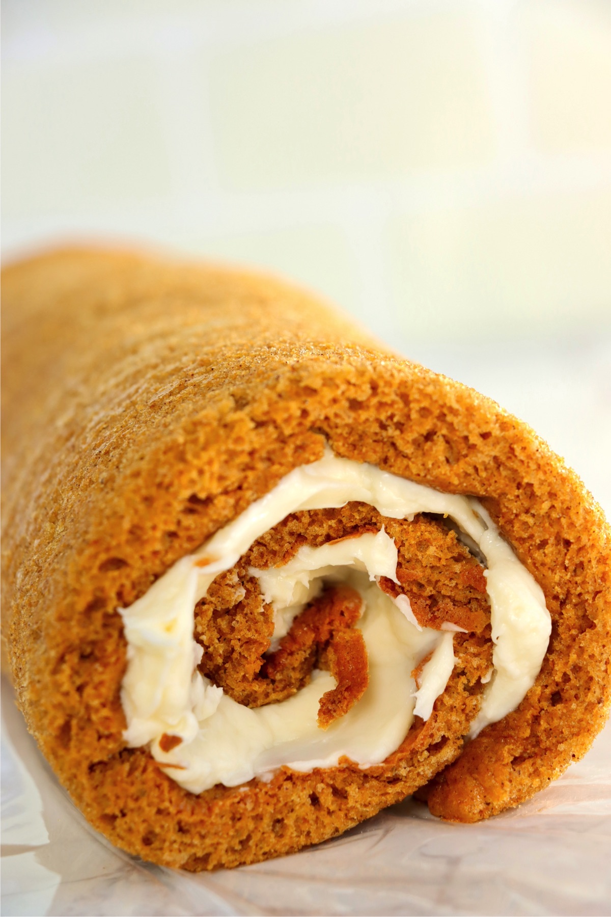 Rolled up pumpkin cake roll with a cream cheese frosting swirl.