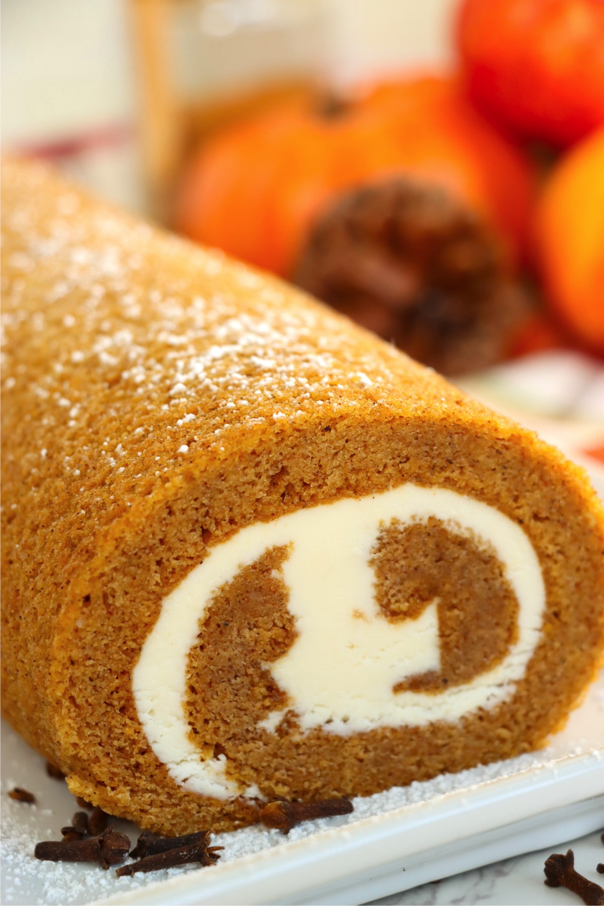 A beautifully swirled pumpkin roll filled with a cream cheese filling and sprinkled with powdered sugar.