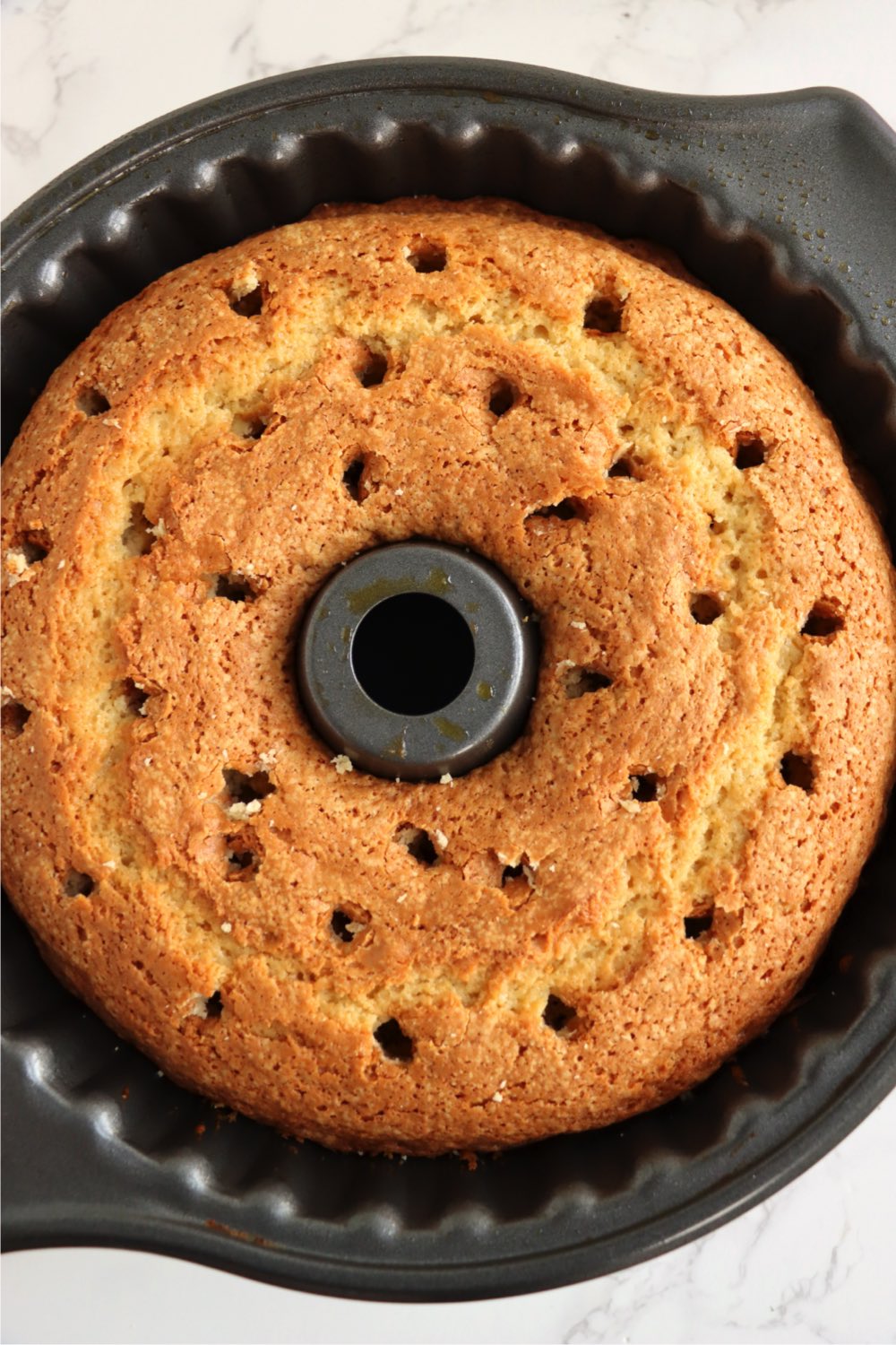 Baked salted caramel kentucky butter cake recipe baked in bundt pan with holes poked in it.