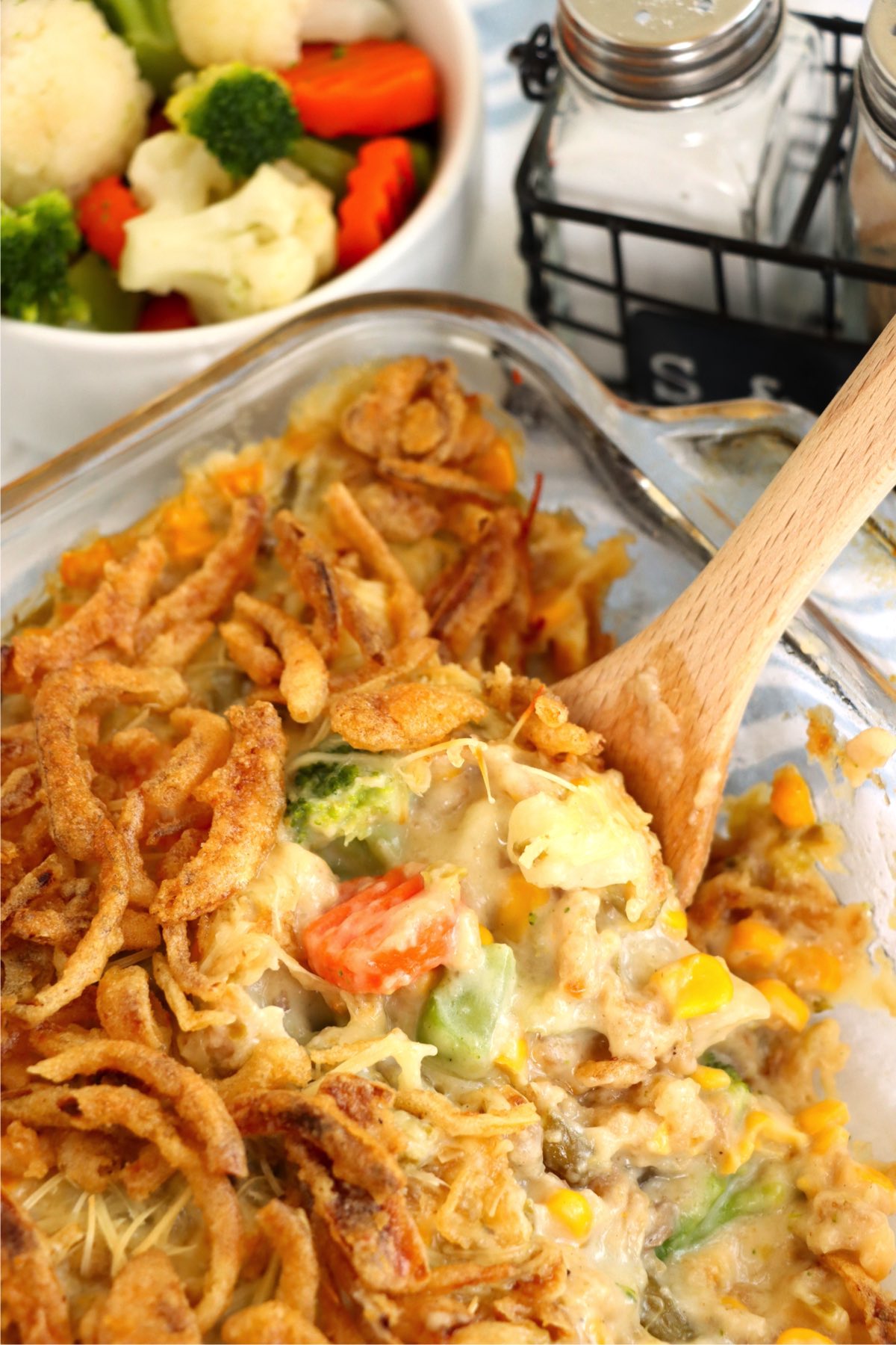 Serving spoon digging into a baking dish filled with a vegetable casserole.