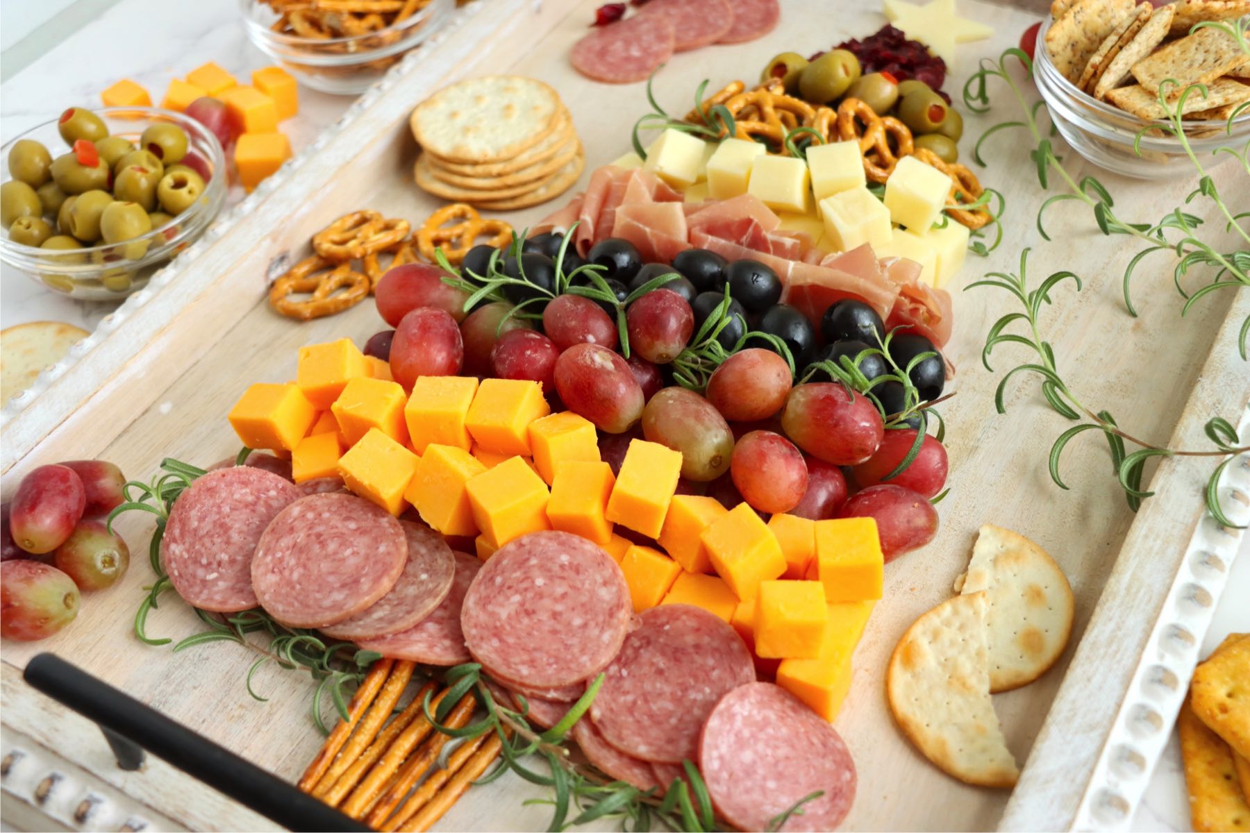 Christmas-themed charcuterie board arranged with meats, cheeses, and pretzels in a tree shape.