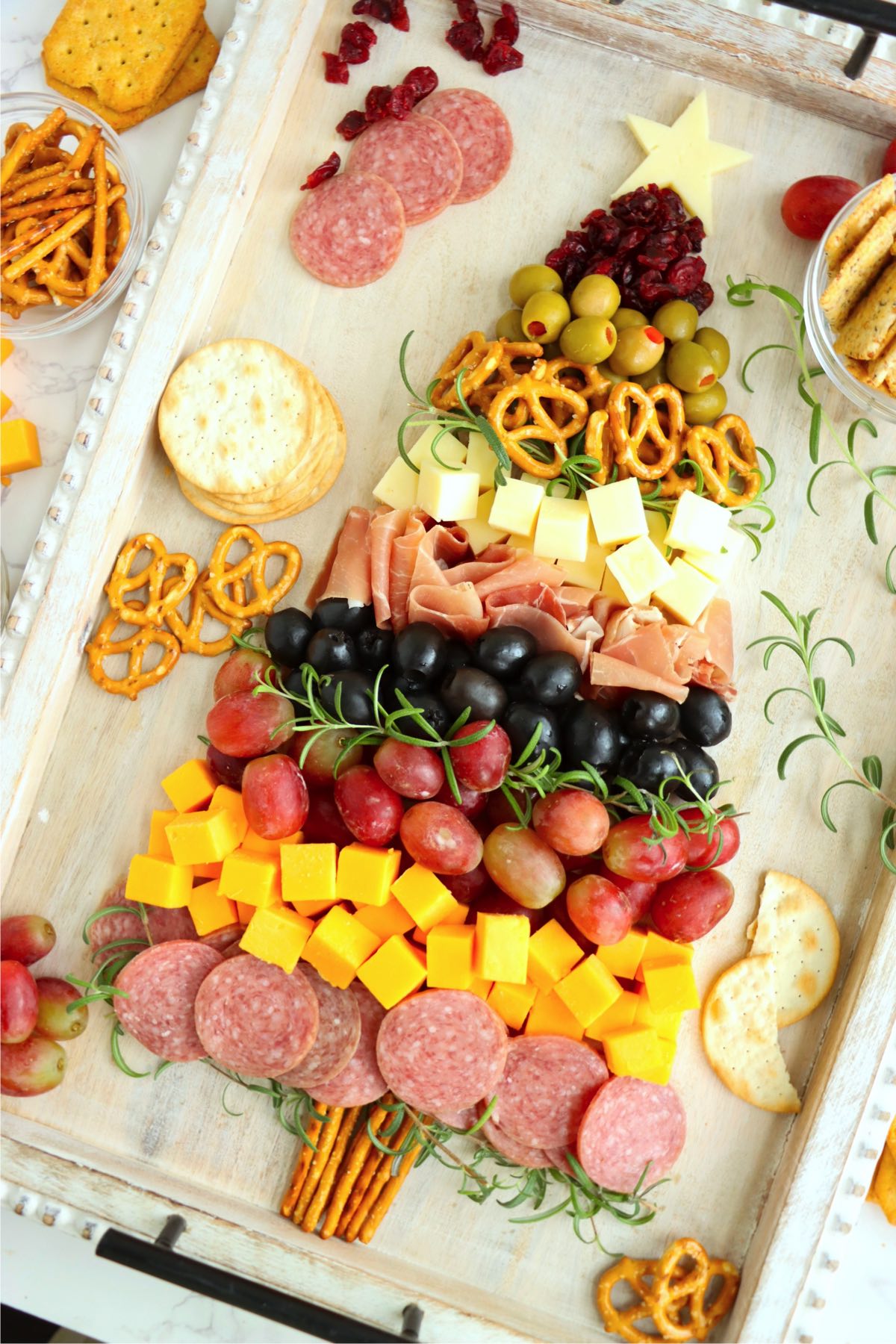 Festive and delicious charcuterie board featuring meats, cheeses, and pretzels arranged as a Christmas tree.