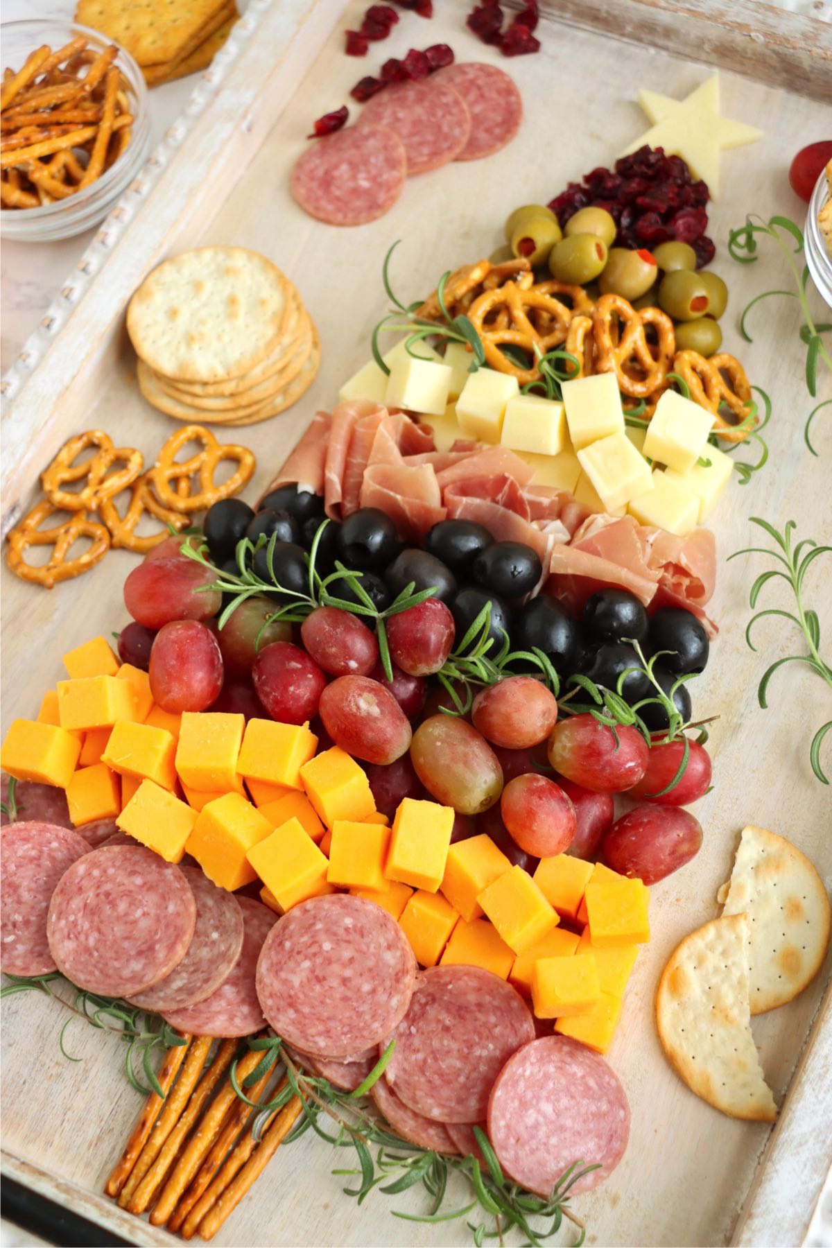 Charcuterie board made of meats, cheeses, pretzel and more in the shape of a Christmas tree.