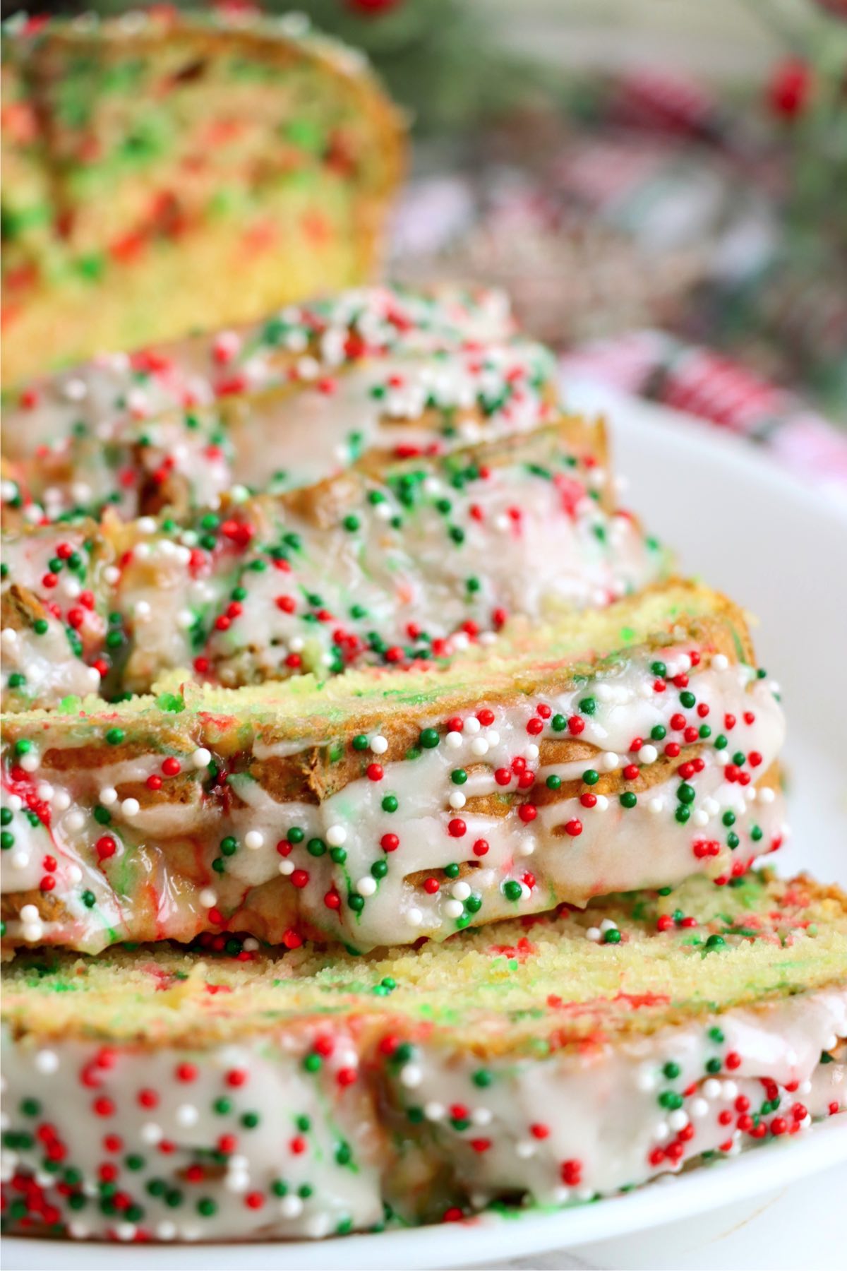 Christmas bread with sprinkles cut into slices on a white plate.