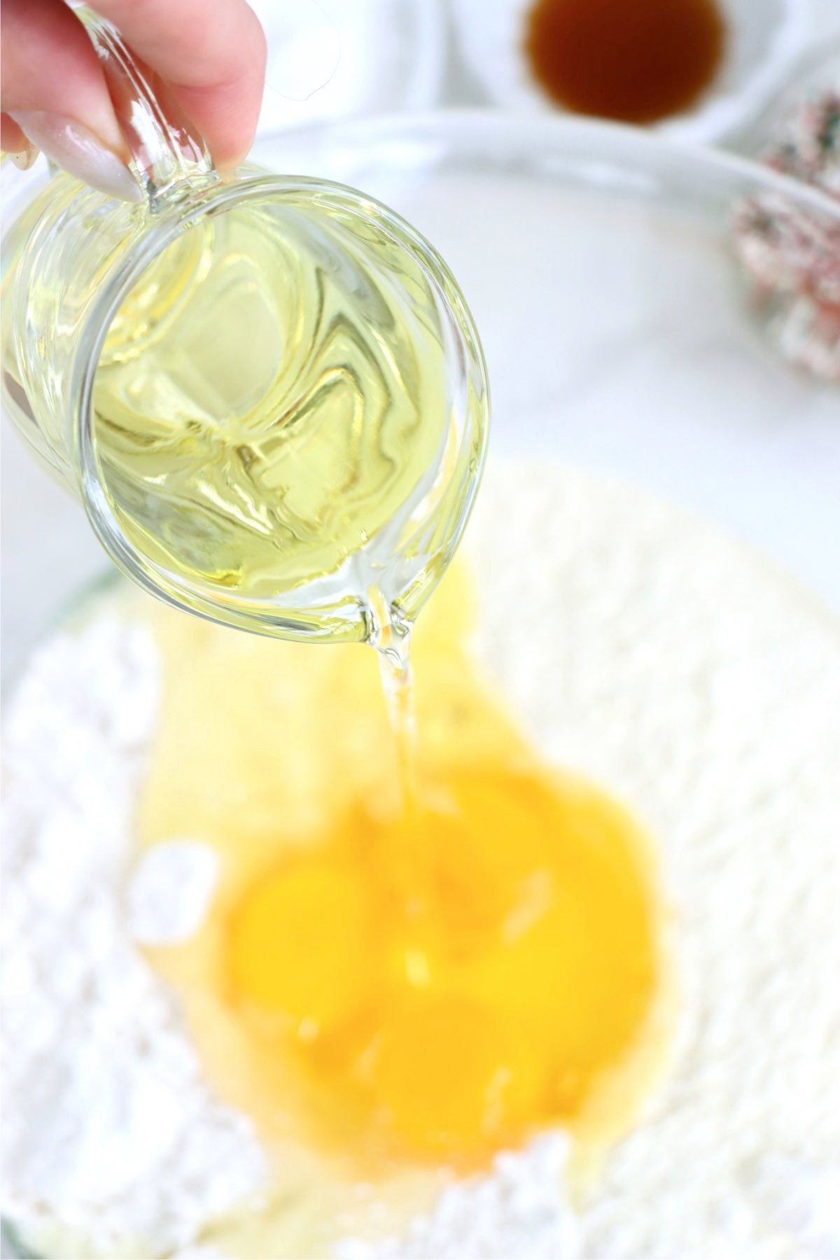 Pouring oil into a bowl filled with cake mix and eggs.