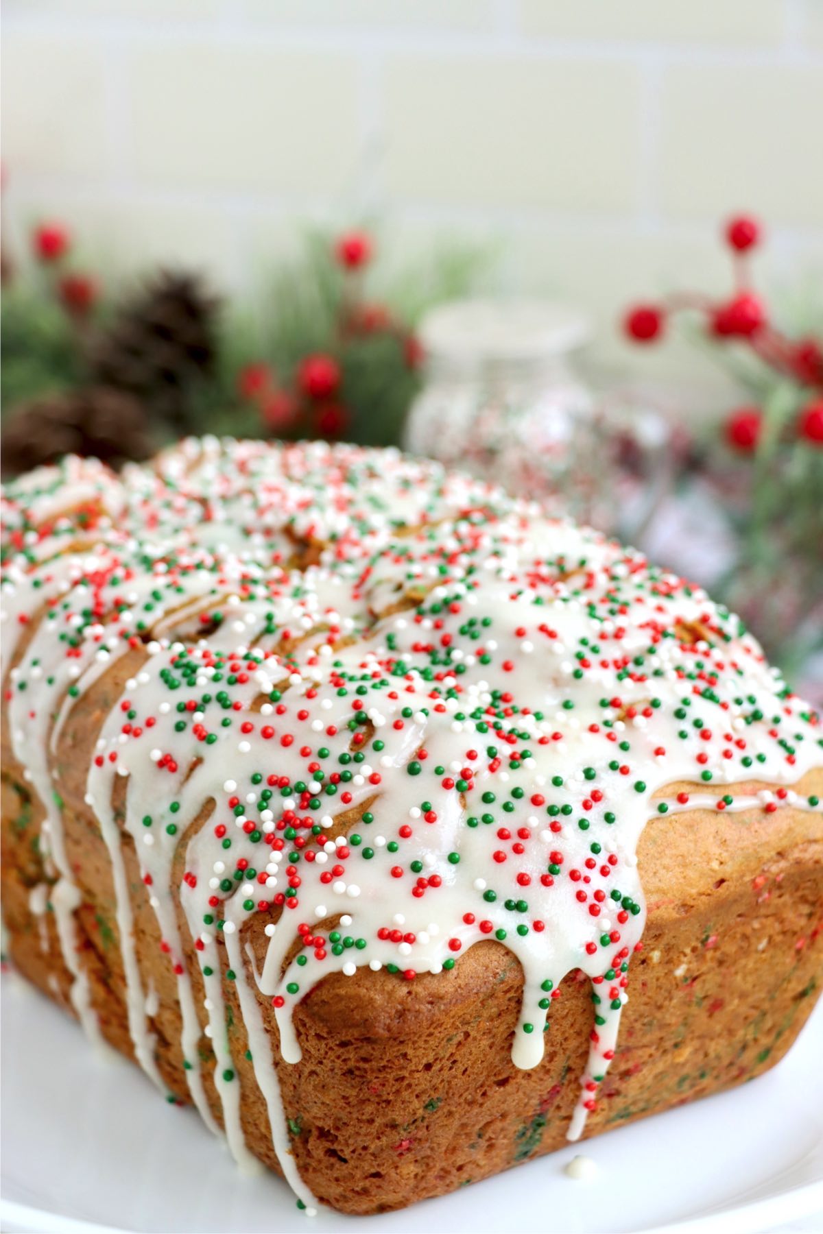 Loaf of Christmas Bread covered with icing and red and green sprinkles.