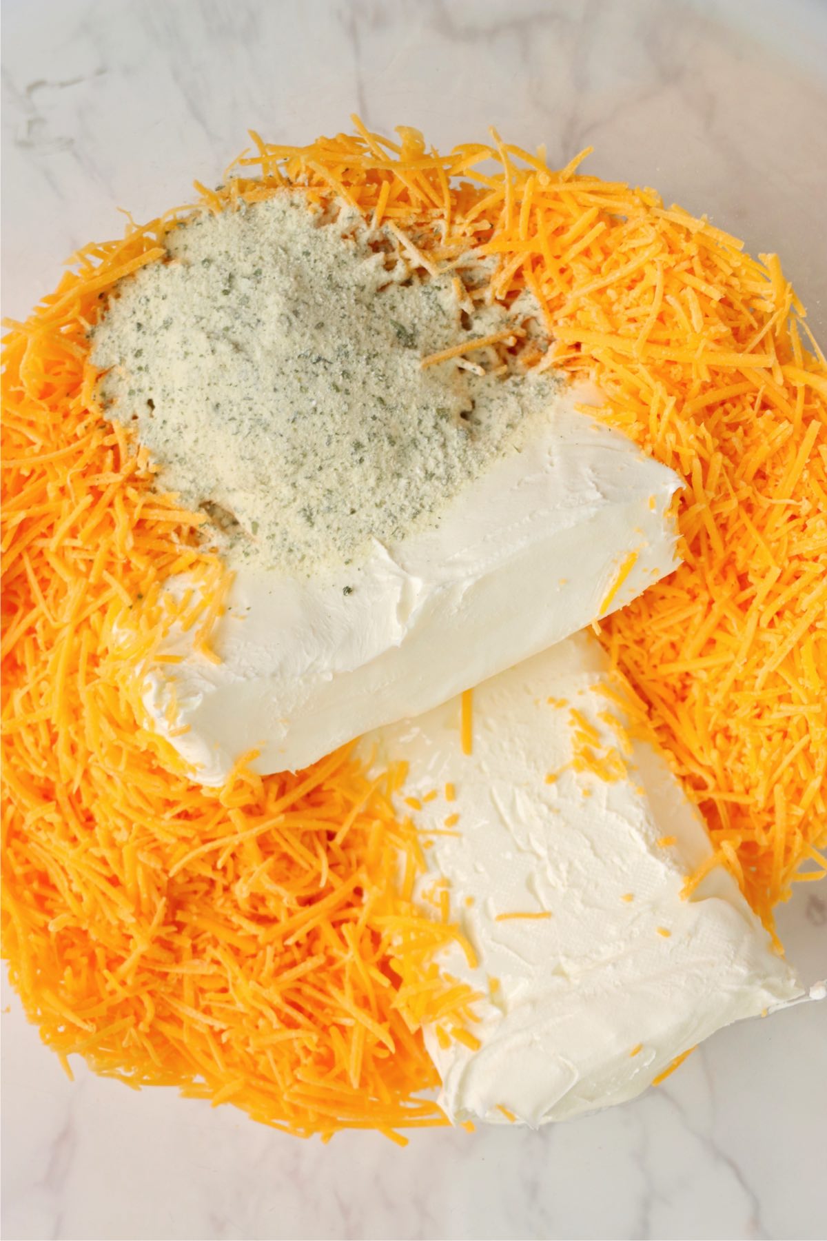 Cream cheese, shredded sharp cheddar cheese, and ranch seasoning in a mixing bowl