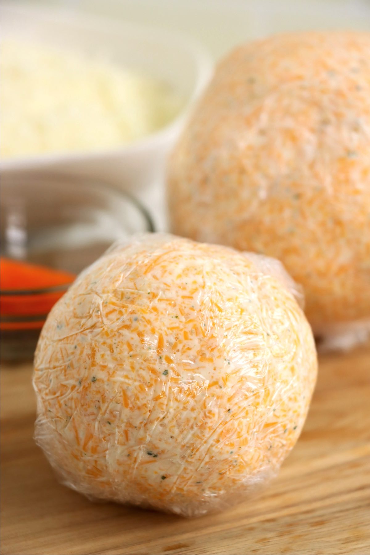 Two cheese balls wrapped in plastic wrap.