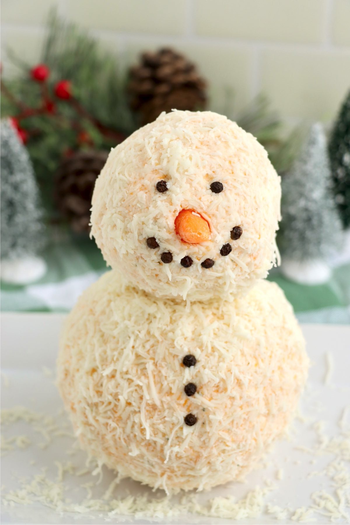 Snowman cheese ball with baby carrot nose and peppercorn eyes, mouth and buttons.