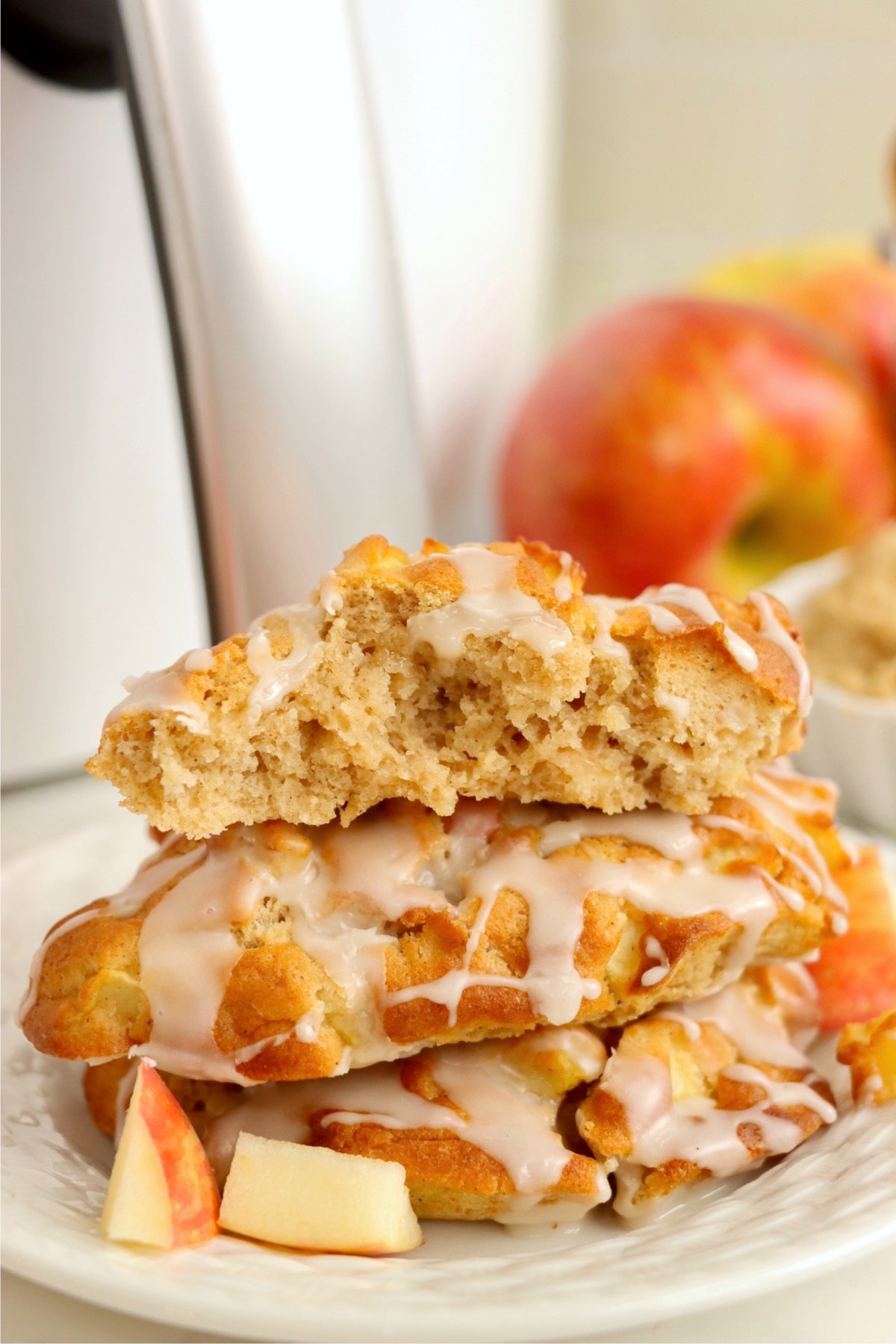 Bite out of an apple fritter on the top of the stack of three.