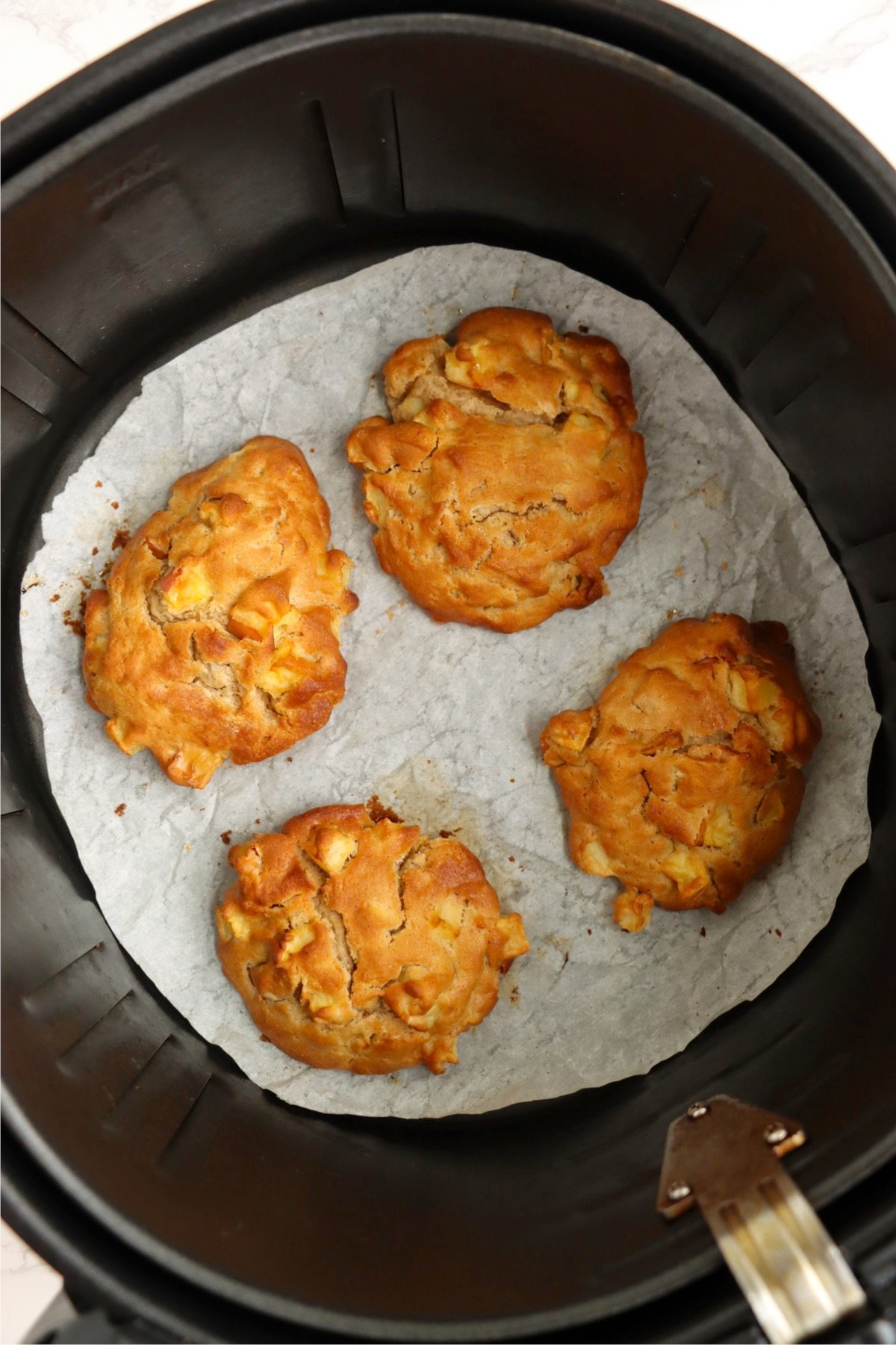 Golden-brown apple fritters fresh out of the air fryer, perfectly crisp and ready to glaze.