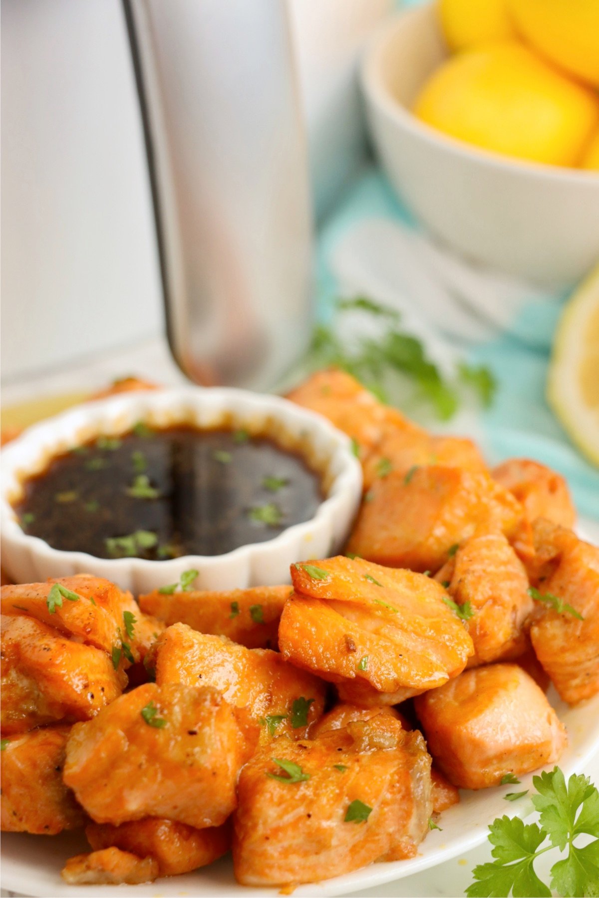 Air fryer salmon bites paired with fresh lemons and parsley for added flavor.