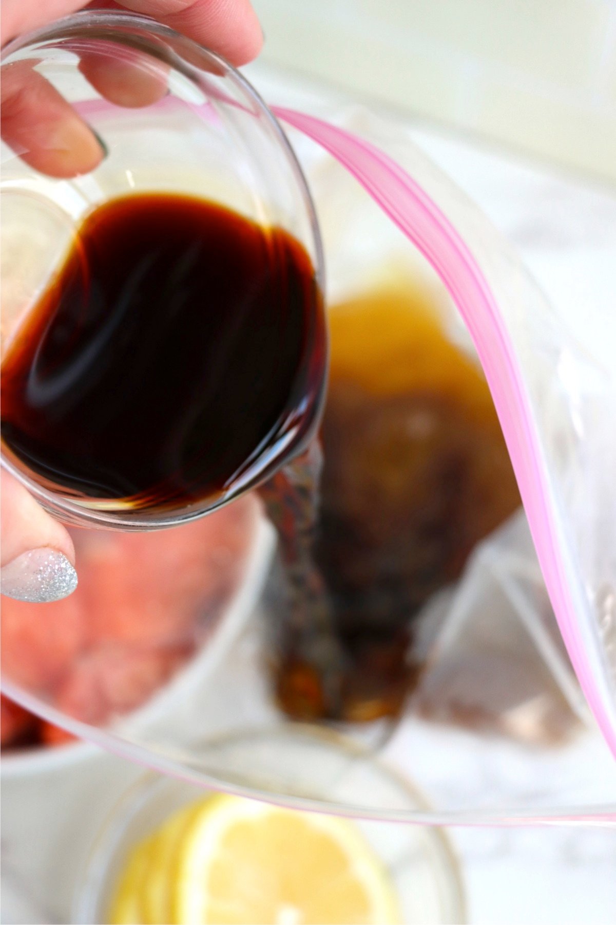 Pouring soy sauce marinade into a ziplock bag for perfectly seasoned air fryer salmon bites.