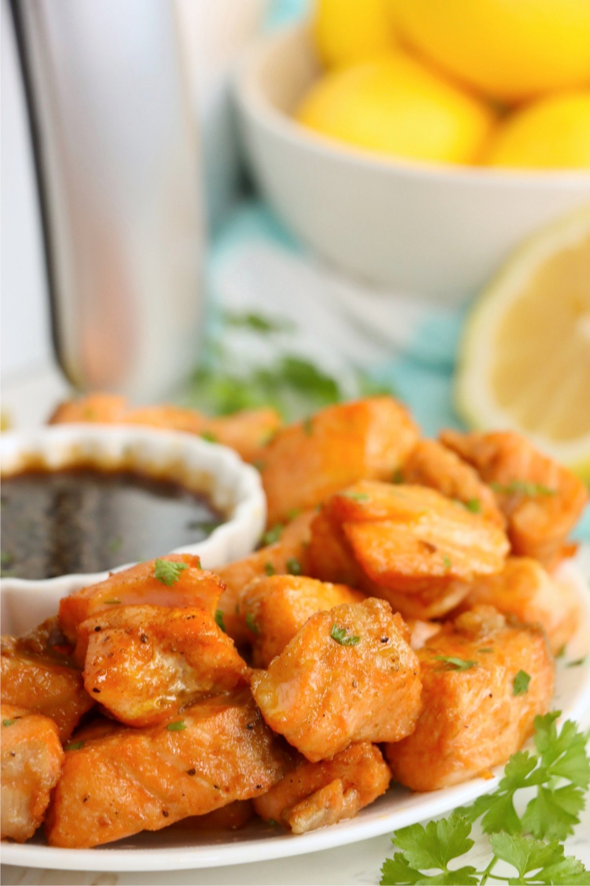 A plate of golden-brown air fryer salmon bites garnished with parsley and served with a dipping sauce.