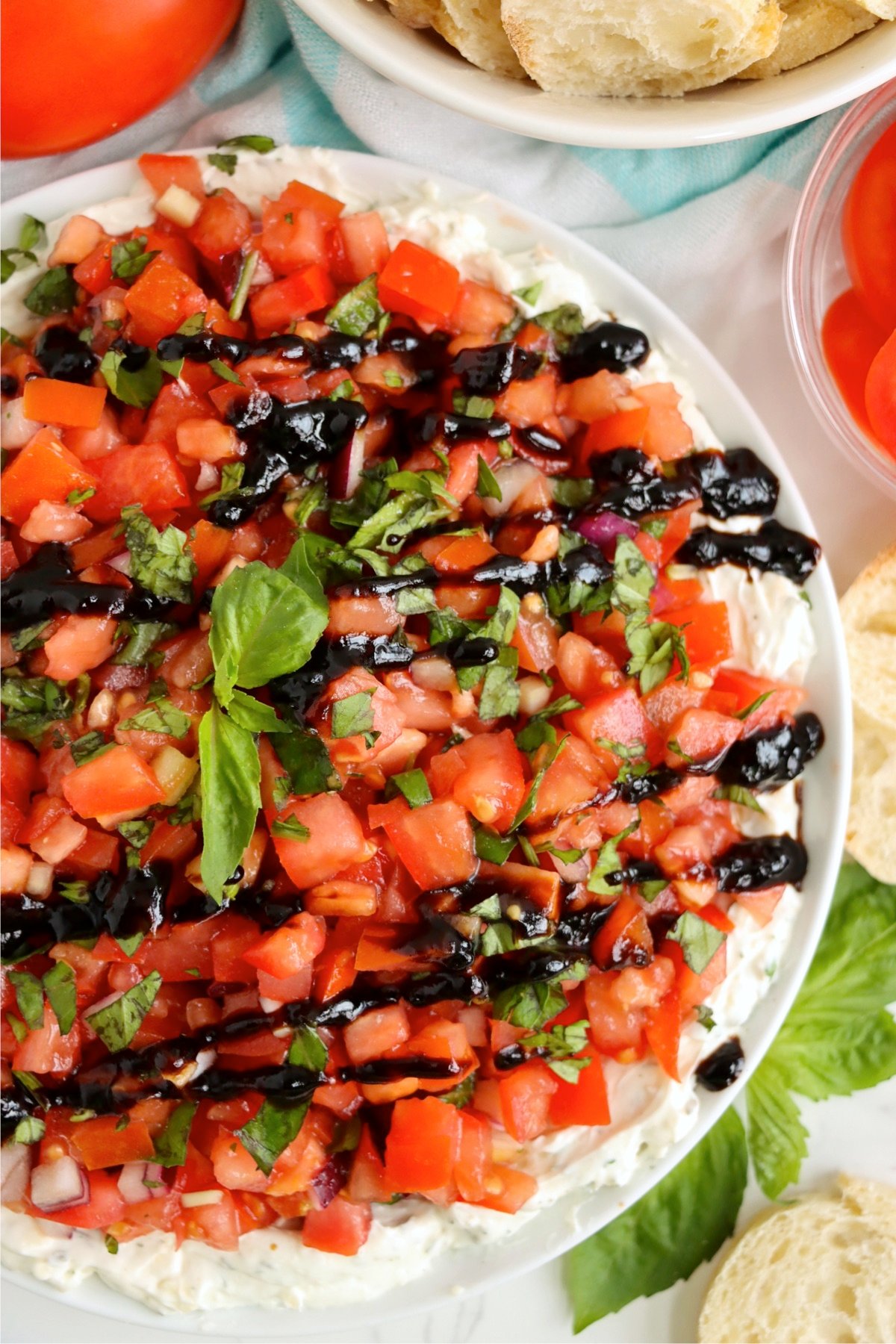 White plate of bruschetta dip drizzled with balsamic glaze.