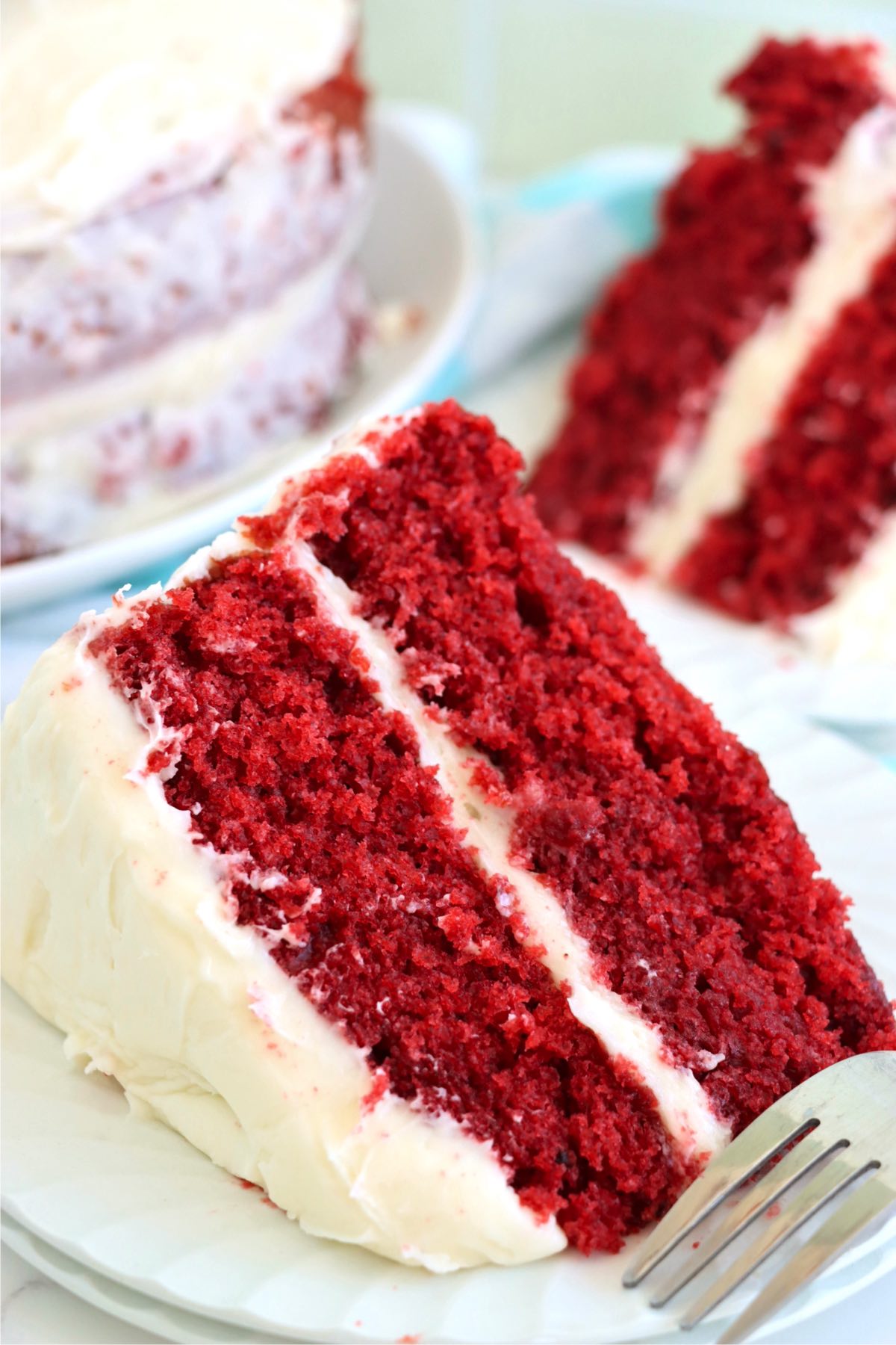 Slice of layered red velvet cake on a white plate.