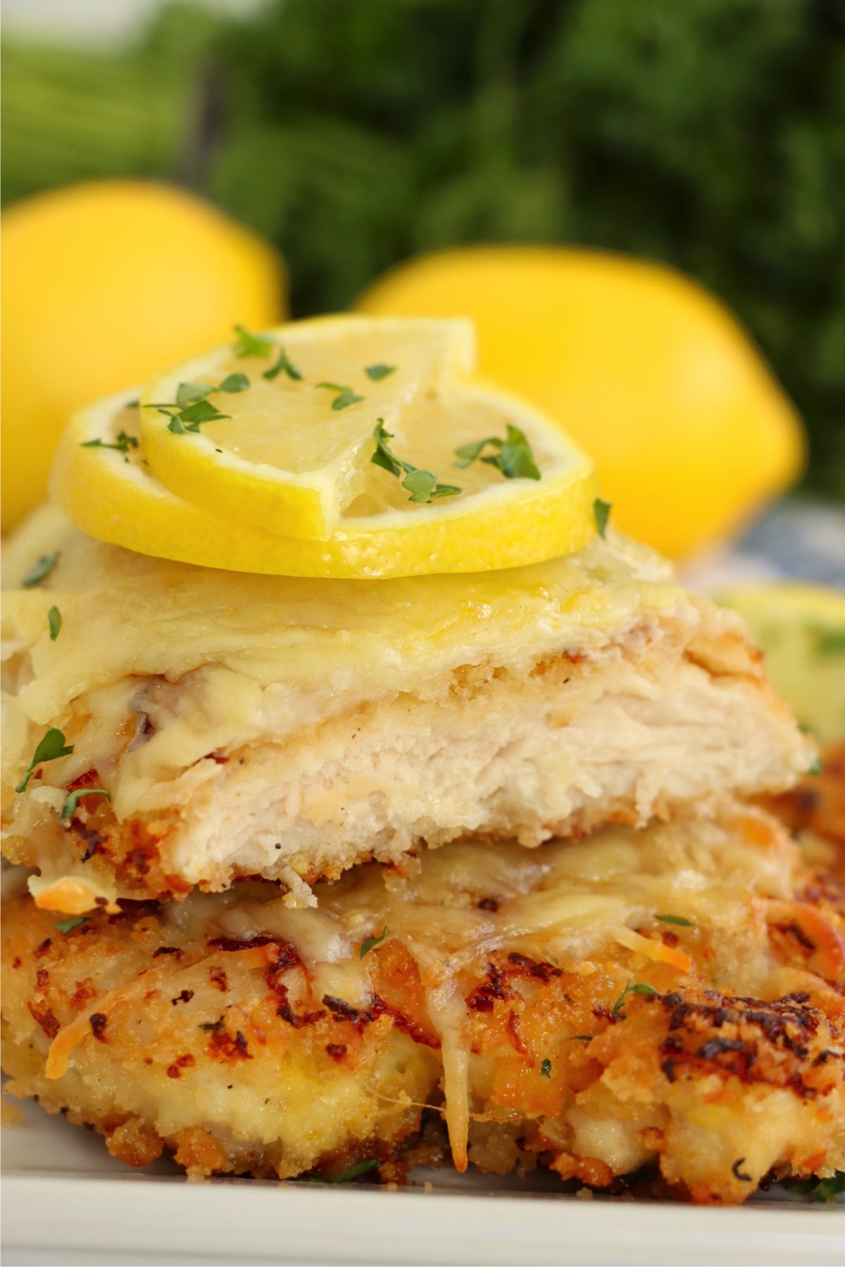 Two pieces of Lemon Chicken Romano stacked, revealing the tender, juicy inside of the chicken, encased in a crispy, cheesy, golden-brown crust.