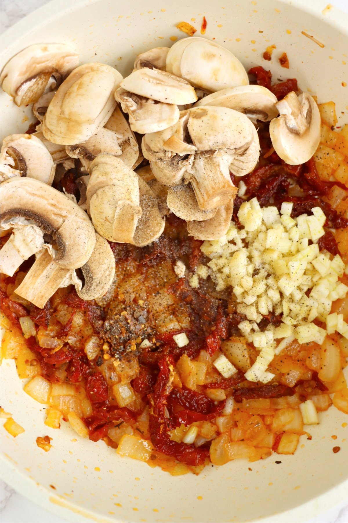 Mushrooms, garlic, and spices added to the skillet with onions and sun-dried tomatoes, building the dish’s rich flavor.